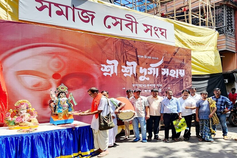 *সমাজের যে সমস্ত মানুষ বর্ণ ধর্ম নির্বিশেষে দুর্গাপুজোয় শামিল হন আড়ালে থেকে, একটানা পরিশ্রম করে কাজ করে পুজো মণ্ডপ সাজিয়ে তোলেন, প্রতিমা বয়ে নিয়ে আসেন, মণ্ডপে ফুল-ফল থেকে শুরু করে ভোগ রান্না সমস্ত কিছুতেই যাদের নিঃশব্দ অবদান তাদের কথা মাথায় রেখে এ বার সমাজসেবী। 