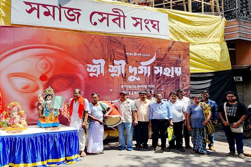 *পুজো কমিটি ঠিক করেন এই মানুষগুলোর হাতেই পুজোর ব্যানার উন্মোচন করা হবে। যেমন ভাবা তেমনই কাজ। পুরোহিত সঞ্জয় গঙ্গোপাধ্যায় থেকে শুরু করে বিদ্যুৎ কর্মী সন্দীপ পাল, সুজয় রাহা। খাদ্য সরবরাহকারী নোটন তালুকদার, মণ্ডপ শয্যার কর্মী কৃষানু পাল, দীপ কুমার দেব। পুজো মণ্ডপের সামনে যারা ভুট্টা, হাওয়াই মিঠাই বিক্রি করেন, সেই তপন দাস ও গদাই সবাইকেই নিমন্ত্রণ করা হয়। বিশ্বকর্মা ও গণেশ দুই পুজোর কথা মাথায় রেখে দুই প্রতিমা সামনে রেখে হাসিমুখেই ব্যানার উন্মোচন করেন তাঁরা।