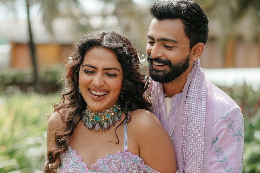 ল্যাভেন্ডার রঙে সেজেছেন নবদম্পতি। লহেঙ্গা পরে অমলা, জগতের পরনে শেরওয়ানি। কখনও ফুলের মাঝখান দিয়ে হেঁটে আসছেন যুগল। কখনও আবার হাতে ফুল নিয়ে সিঁড়ি দিয়ে নামছেন। অপরূপ দেখাচ্ছে দু’জনকেই।