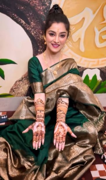 সবুজ সিল্কের শাড়ি পরেছিলেন তিনি৷ দু’হাত ভরে পরেছেন মেহন্দি৷ তাতে আবার রয়েছে তাদের দু’জনের মুখ৷ 