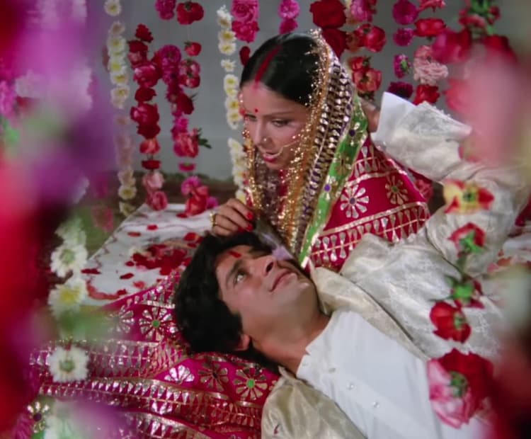 *'কভি কভি মেরে দিল মে' গানটি গেয়েছেন লতা মঙ্গেশকর, যেখানে একদিকে কনে তার প্রাক্তন প্রেমিককে (অমিতাভ বচ্চন) বিয়ের রাতে স্মরণ করে দুঃখে বিভোর। অন্যদিকে, তিনি তার স্বামীর (শশী কাপুর) বাহুডোরে মুখ লুকিয়েছেন লজ্জায়। (ছবি সৌজন্যে: YouTube@Videograb)