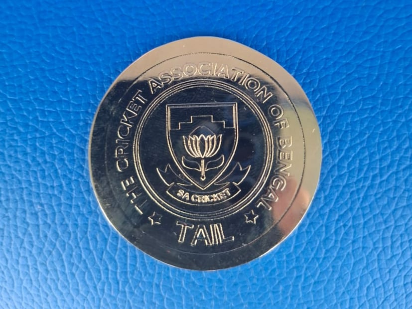 ইডেনে টসের কয়েনের অপরদিকে, লেখা ক্রিকেট অ্যাসোসিয়েশন অফ বেঙ্গল, সঙ্গে রয়েছে দক্ষিণ আফ্রিকা ক্রিকেট বোর্ডের লোগো, লেখা রয়েছে টেল। 