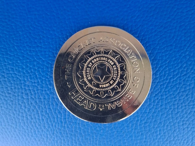 সোনার যে বিশেষ কয়েন দিয়ে ভারত বনাম দক্ষিণ আফ্রিকার প্রথম টেস্টে তাদে একদিকে লেখা রয়েছে ক্রিকেট অ্যাসোসিয়েশন অফ বেঙ্গল। বিসিআইয়ের লোগো ও হেটড লেখা।