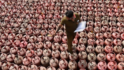 A worker inspects liquefied petroleum gas cylinders, arranged for customer delivery at a distribution centre on the outskirts of Amritsar, India, Friday, March 13, 2026. (AP Photo/Prabhjot Gill)