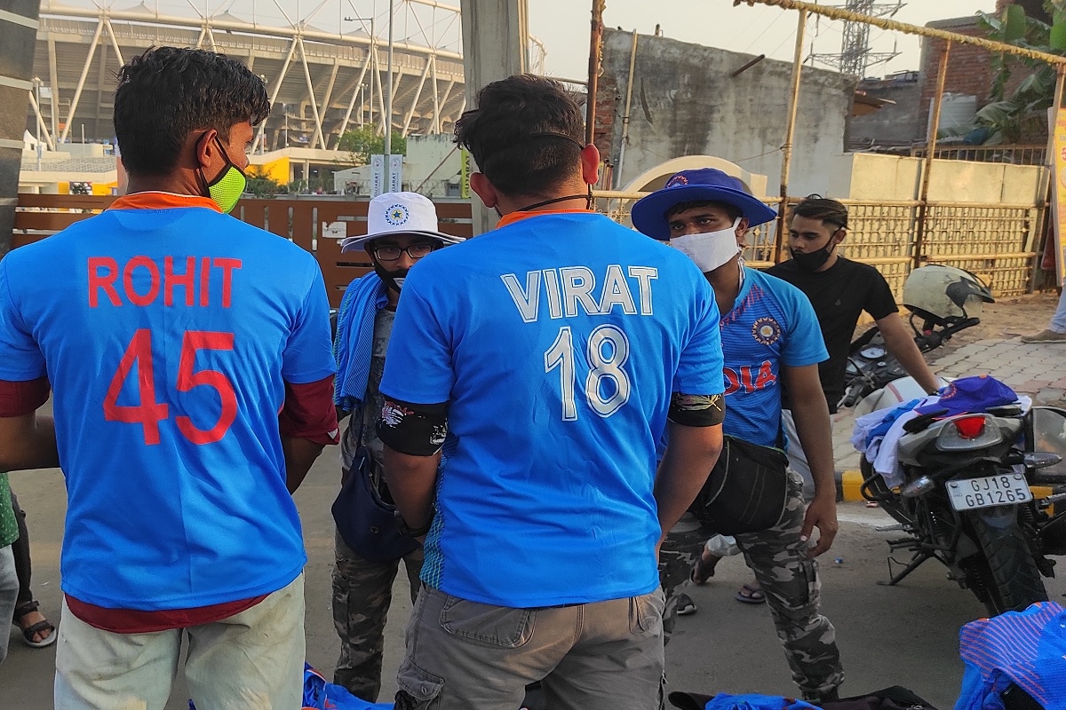 સંજય ટાંક, અમદાવાદ: ક્રિકેટ રમીને વર્ષે કરોડો રૂપિયાની કમાણી ભારતીય ક્રિકેટ ટીમના (Indian cricket team) ખેલાડીઓ કરે છે પણ આ ખેલાડીઓ ફેન્સ (fans) પણ એટલા તેમના પાછળ એટલા ક્રેઝી થઈ જાય છે કે ના પૂછો વાત. વિશ્વના સૌથી મોટા સ્ટેડિયમ (stadium) પર ભારત અને ઇંગ્લેન્ડ (India-England test match) વચ્ચે ટેસ્ટ રમવાની છે. ત્યારે મોટેરા સ્ટેડિયમમાં ટેસ્ટ ક્રિકેટ મેચ નિહાળવા માટે ટીકીટ ખરીદીમાં તો ક્રિકેટ રસિકોએ લાઈન લગાવી પણ સાથે સાથે ક્રિકેટના ખેલાડીઓના નામની ટીશર્ટ ખરીદવામાં પણ ક્રેઝી ફેન્સએ પડાપડી કરી. અને એમાં જ વિરાટ (virat) સ્ટેડિયમની બહાર 200 રૂપિયામાં વેચાયો. સંજય ટાંક, અમદાવાદ: ક્રિકેટ રમીને વર્ષે કરોડો રૂપિયાની કમાણી ભારતીય ક્રિકેટ ટીમના (Indian cricket team) ખેલાડીઓ કરે છે પણ આ ખેલાડીઓ ફેન્સ (fans) પણ એટલા તેમના પાછળ એટલા ક્રેઝી થઈ જાય છે કે ના પૂછો વાત. વિશ્વના સૌથી મોટા સ્ટેડિયમ (stadium) પર ભારત અને ઇંગ્લેન્ડ (India-England test match) વચ્ચે ટેસ્ટ રમવાની છે. ત્યારે મોટેરા સ્ટેડિયમમાં ટેસ્ટ ક્રિકેટ મેચ નિહાળવા માટે ટીકીટ ખરીદીમાં તો ક્રિકેટ રસિકોએ લાઈન લગાવી પણ સાથે સાથે ક્રિકેટના ખેલાડીઓના નામની ટીશર્ટ ખરીદવામાં પણ ક્રેઝી ફેન્સએ પડાપડી કરી. અને એમાં જ વિરાટ (virat) સ્ટેડિયમની બહાર 200 રૂપિયામાં વેચાયો.
