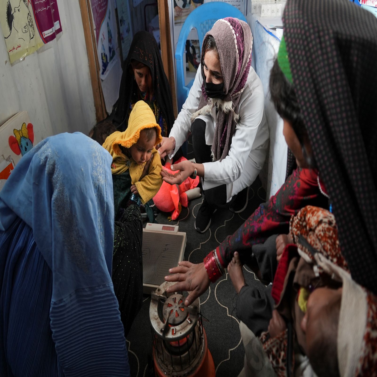 16 دسمبر 2021 کو ہرات، افغانستان کے قریب ایک بستی میں ورلڈ ویژن کے زیر اہتمام عارضی کلینک میں ایک نرس بچے کا وزن چیک کر رہی ہے۔ (اے پی فائل فوٹو)
