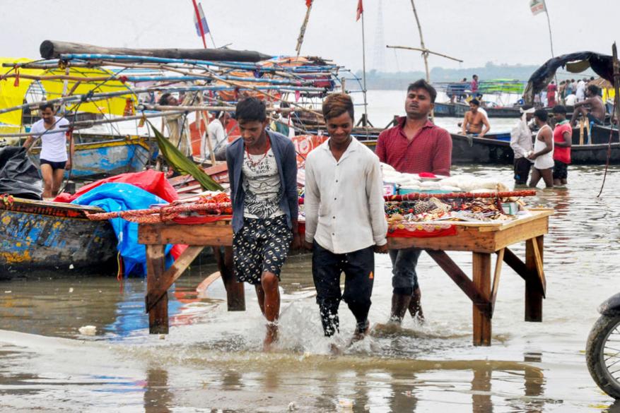 பிரயாகராஜில் பருவமழையால் ஏறபட்ட வெள்ள பெருக்கில் நடந்து வரும் சாலையோர கடை வைத்திருப்பவர்கள் (Image: PTI) பிரயாகராஜில் பருவமழையால் ஏறபட்ட வெள்ள பெருக்கில் நடந்து வரும் சாலையோர கடை வைத்திருப்பவர்கள் (Image: PTI)