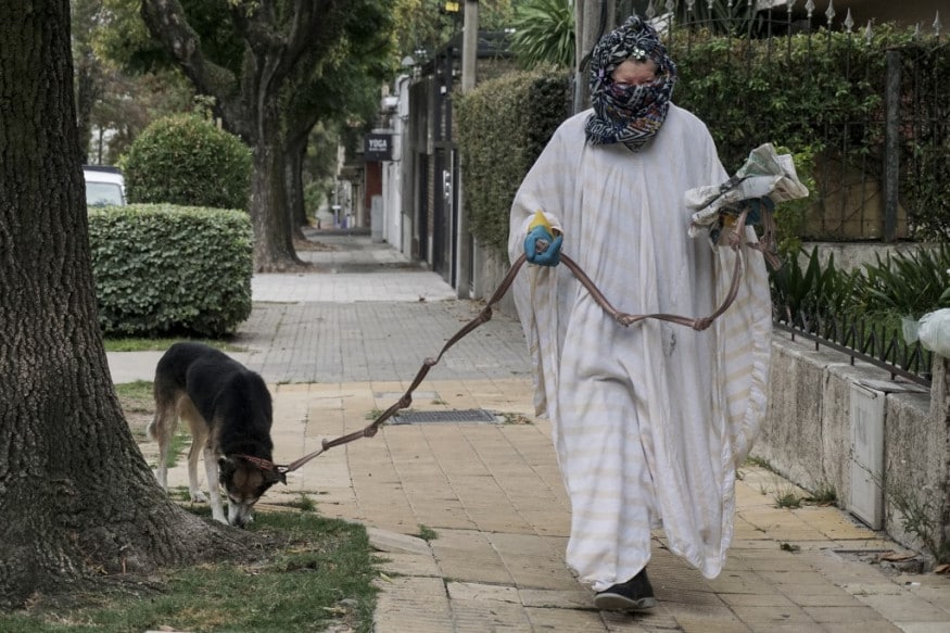 A woman wearing gloves and with her face and body covered against the spread of the novel coronavirus, walks a dog in Montevideo. (Image: AFP) A woman wearing gloves and with her face and body covered against the spread of the novel coronavirus, walks a dog in Montevideo. (Image: AFP)