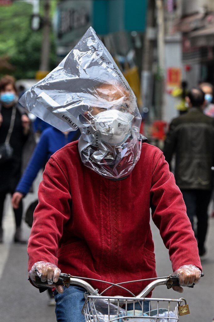 A man wearing a face mask and a plastic bag on his head rides a bicycle on a street in Wuhan, China. (Image: AFP) A man wearing a face mask and a plastic bag on his head rides a bicycle on a street in Wuhan, China. (Image: AFP)