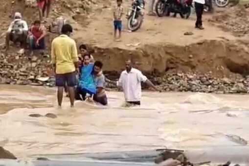 గర్భిణిని వాగు దాటిస్తున్న బంధువులు 